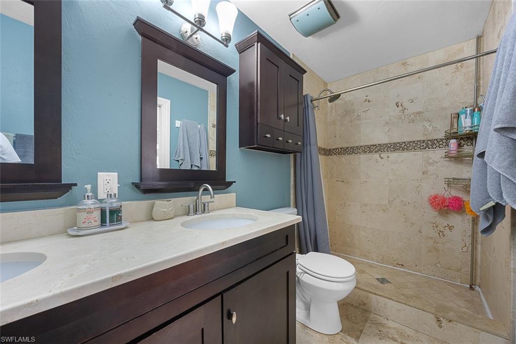 441 3rd Street Southwest Naples, FL 34117 - Photo 19 of 22 Double vanity with integrated sinks, stone-finish countertop, and dark wood cabinetry