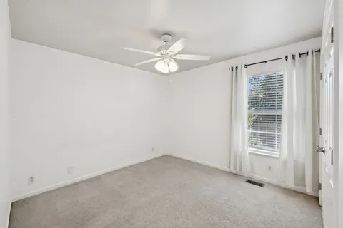 an empty room with a ceiling fan and a window