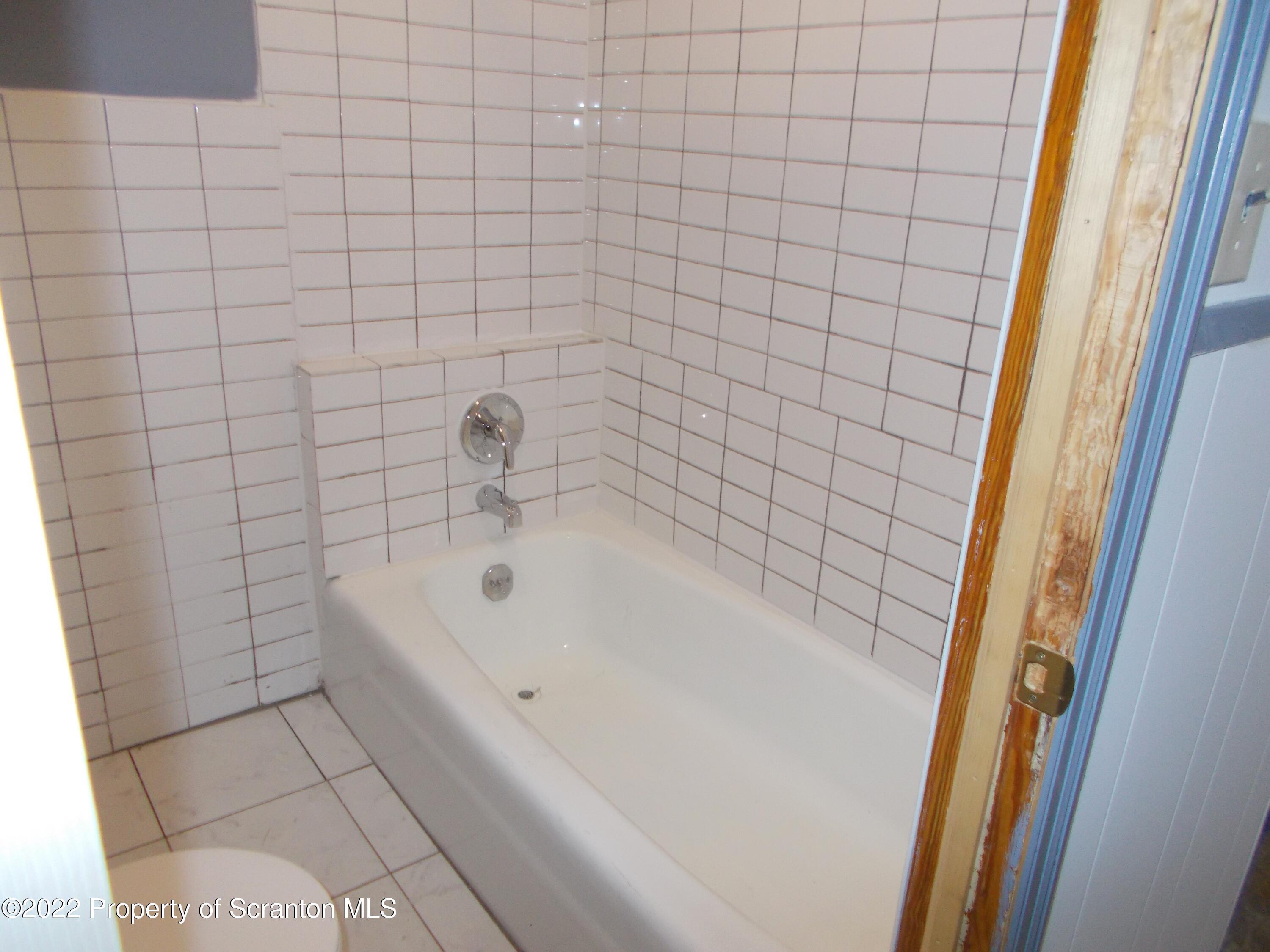 909 Slocum Avenue, Unit 1B Scranton, PA 18505 - Photo 8 of 9 a bathroom with a white bathtub