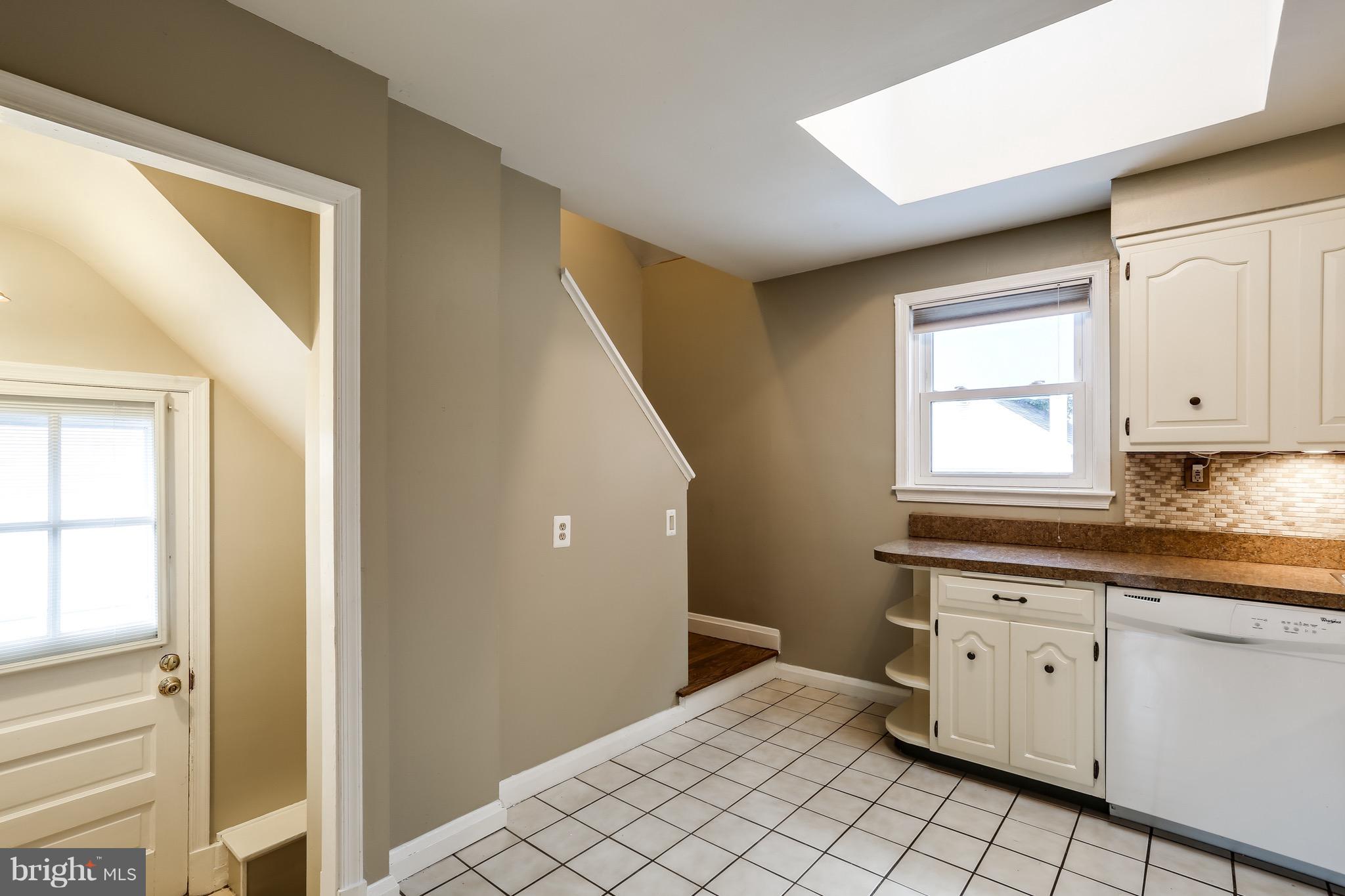 1254 June Road Baltimore, MD 21227 - Photo 14 of 23 a view of a kitchen with white cabinets with wooden floor and window