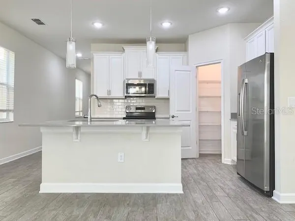 a kitchen with kitchen island a refrigerator a stove a sink and a microwave