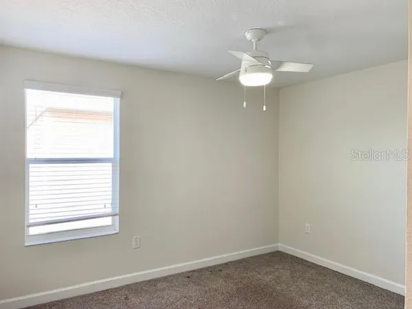 an empty room with a window and a fan