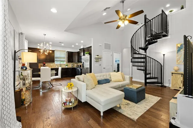 a living room with furniture kitchen view and a wooden floor