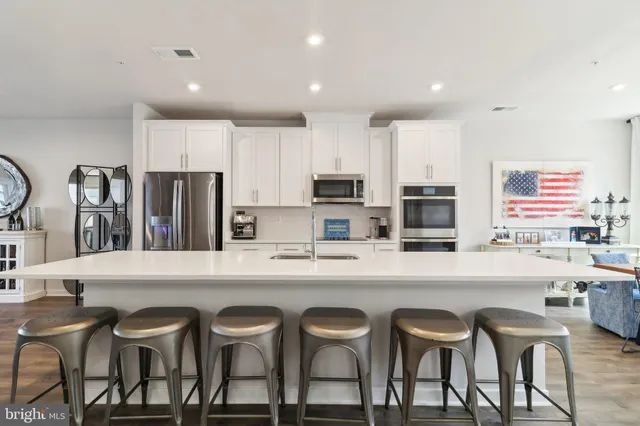 a kitchen with stainless steel appliances granite countertop a table chairs refrigerator and sink