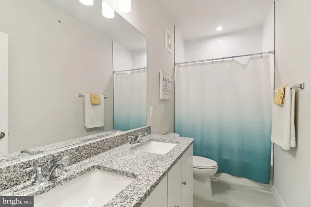 a bathroom with a granite countertop sink toilet and shower
