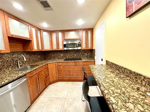 a large kitchen with granite countertop a sink and cabinets