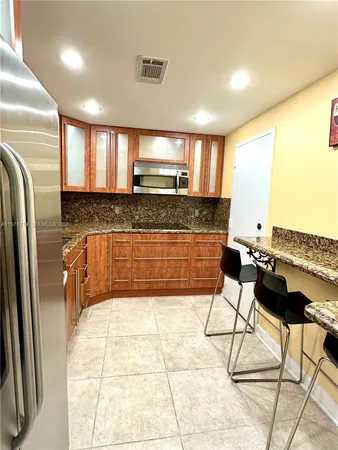 a kitchen with stainless steel appliances granite countertop a sink and a refrigerator