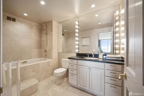 a bathroom with a granite countertop sink a toilet a mirror and shower