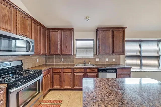 a kitchen with stainless steel appliances granite countertop a stove a sink dishwasher and cabinets with wooden floor