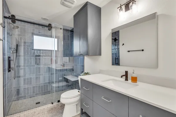 a bathroom with a shower sink vanity mirror and toilet