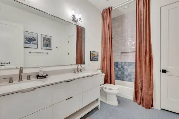 a bathroom with a double vanity sink toilet mirror and shower