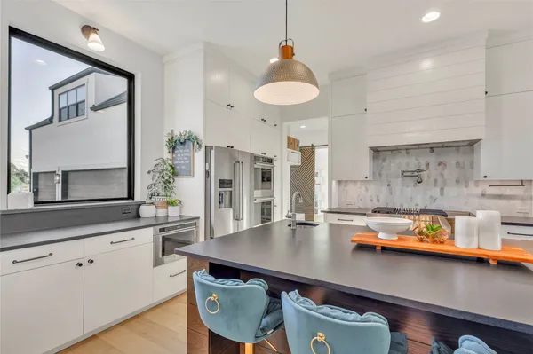 a kitchen with stainless steel appliances a sink a stove and white cabinets