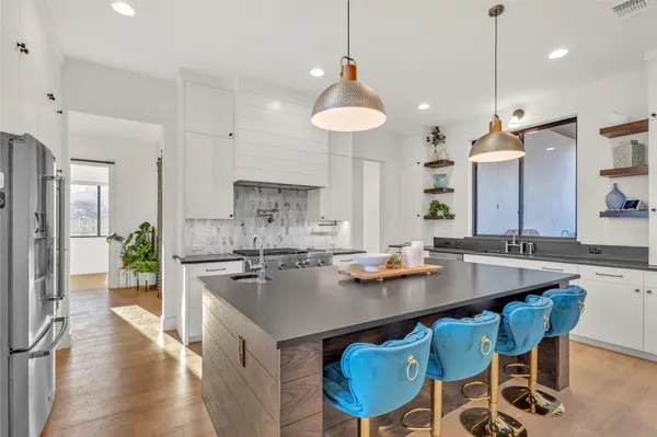 a kitchen with a dining table chairs refrigerator and wooden floor