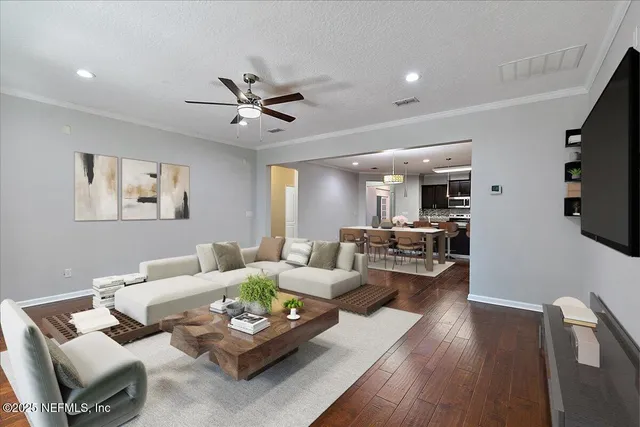 a living room with furniture kitchen view and a wooden floor