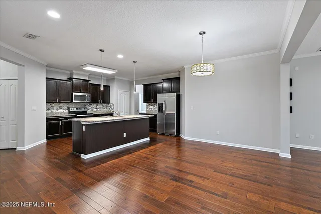 a kitchen with stainless steel appliances granite countertop a refrigerator a sink dishwasher a stove and white cabinets with wooden floor