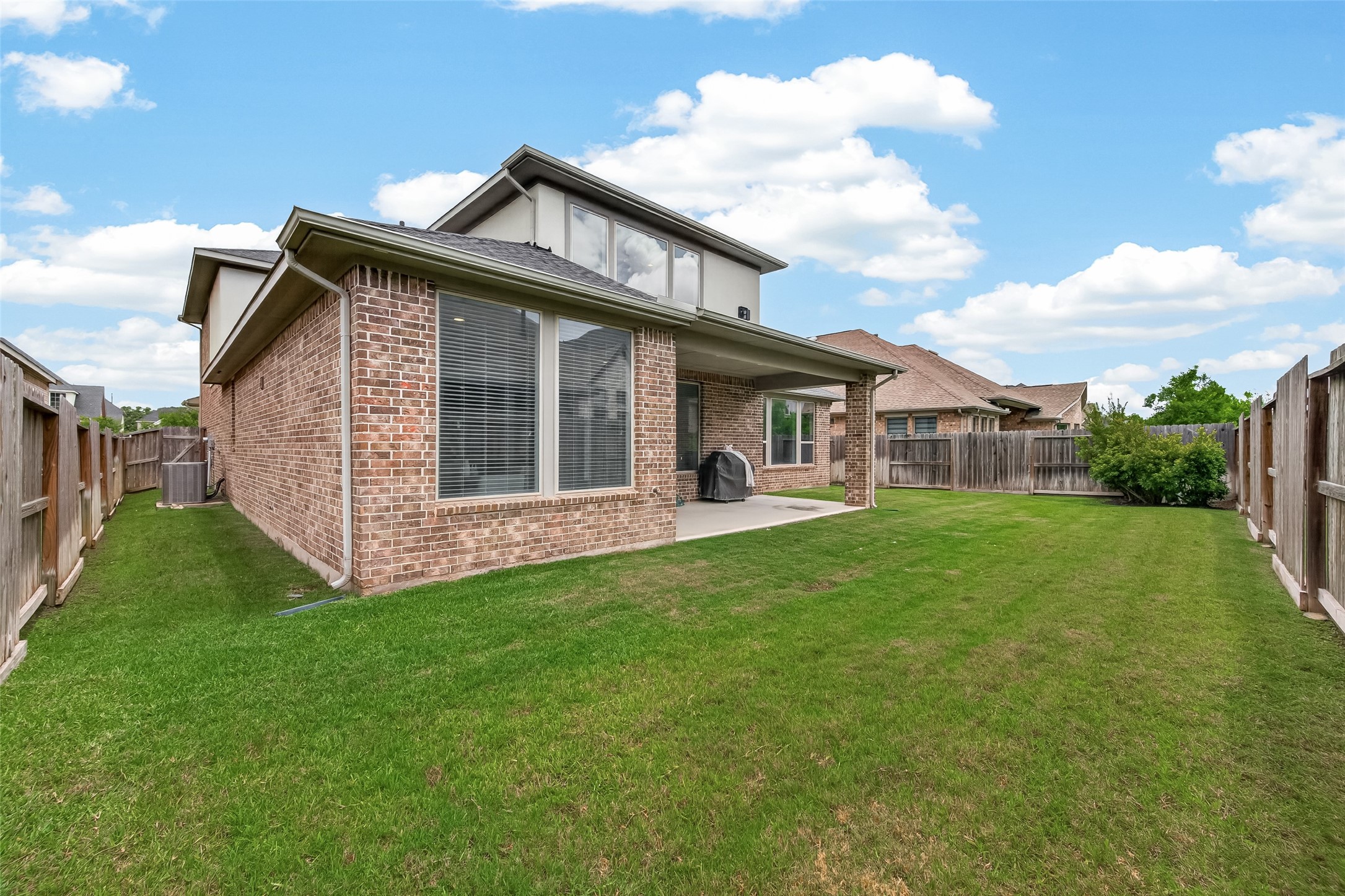 1815 Brea Rdg Trail Katy, TX 77494 - Photo 37 of 43 This photo shows the backyard of a brick house with a spacious lawn, fenced perimeter, and covered patio area, perfect for outdoor activities and relaxation.
