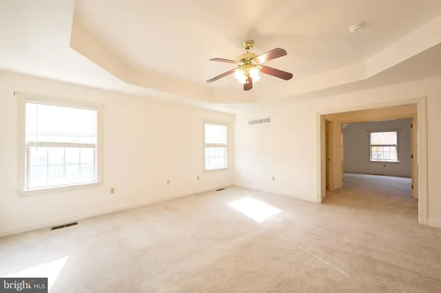 an empty room with windows and fan
