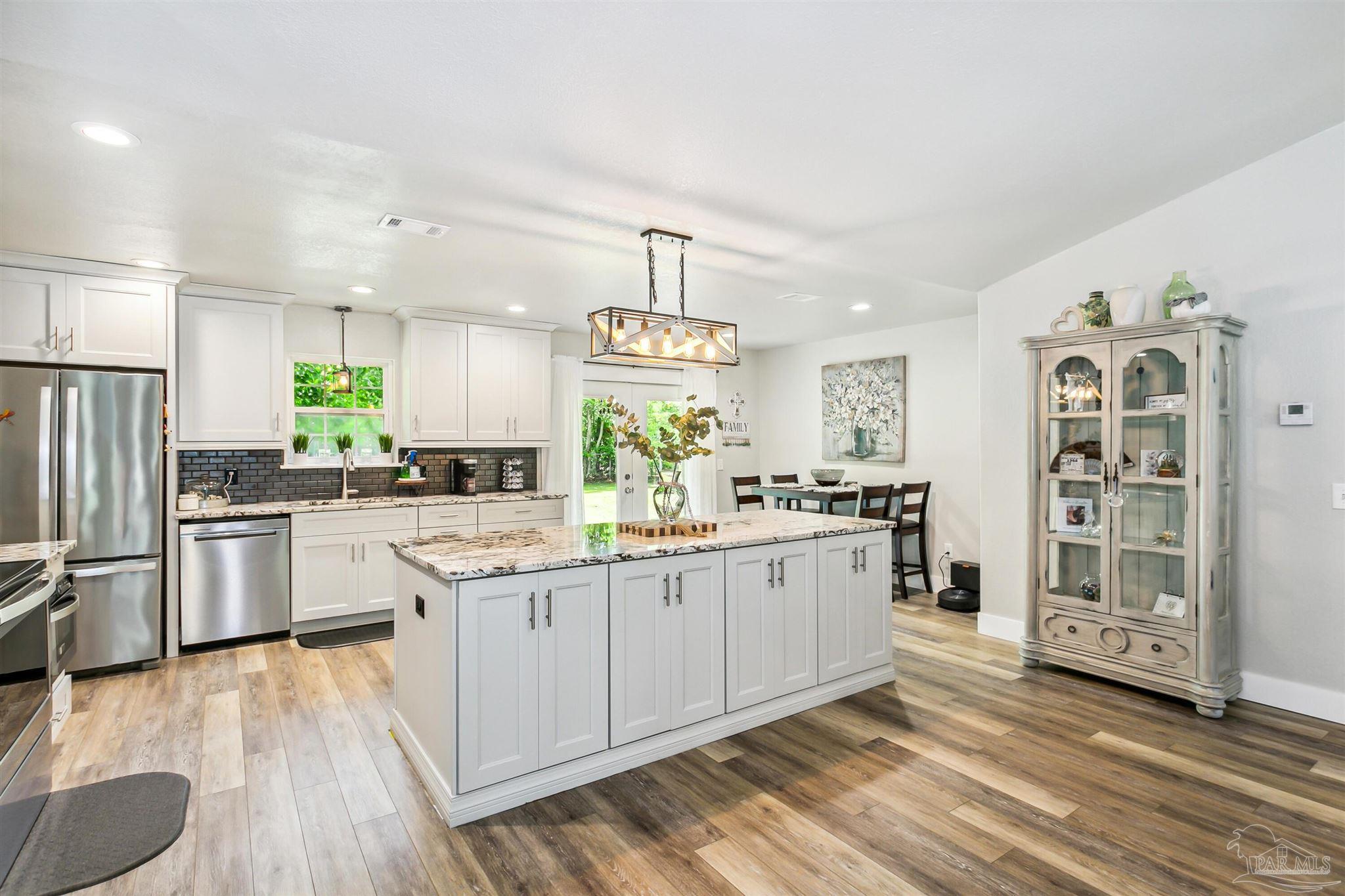 7260 Morrell Road Milton, FL 32583 - Photo 4 of 33 a kitchen with stainless steel appliances a kitchen island hardwood floor sink and wooden floor