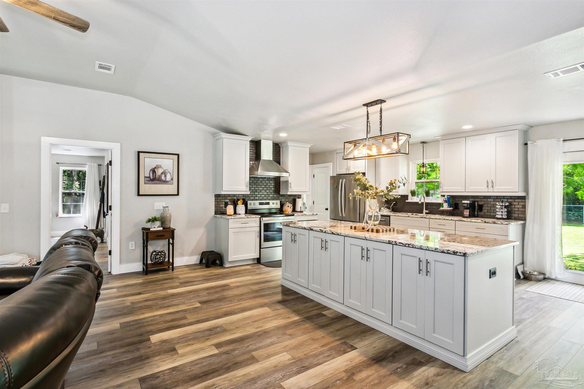 7260 Morrell Road Milton, FL 32583 - Photo 10 of 33 a kitchen with granite countertop a refrigerator a stove a sink dishwasher and white cabinets with wooden floor