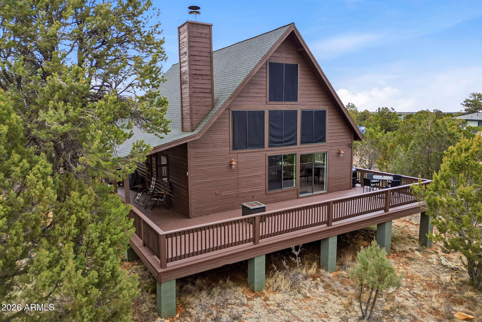a view of a house with wooden deck and a forest