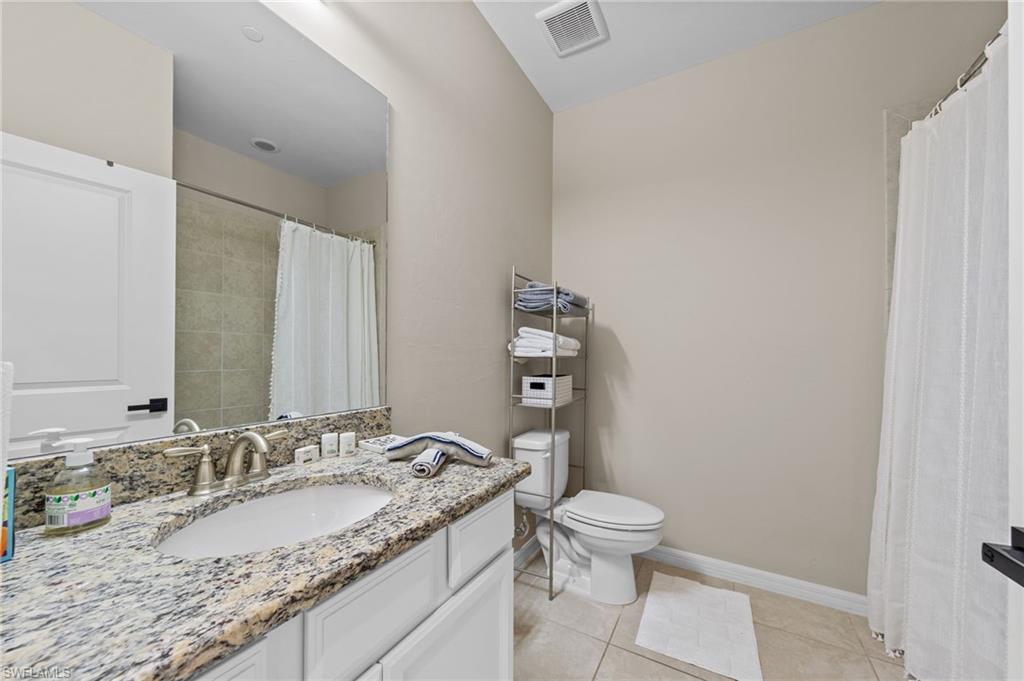 9366 Pocida Court, Unit 202 Naples, FL 34119 - Photo 22 of 44 a bathroom with a granite countertop sink a toilet and a mirror