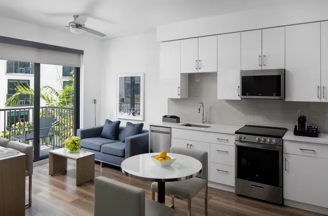 a kitchen with stainless steel appliances granite countertop a stove a sink a microwave a dining table and chairs