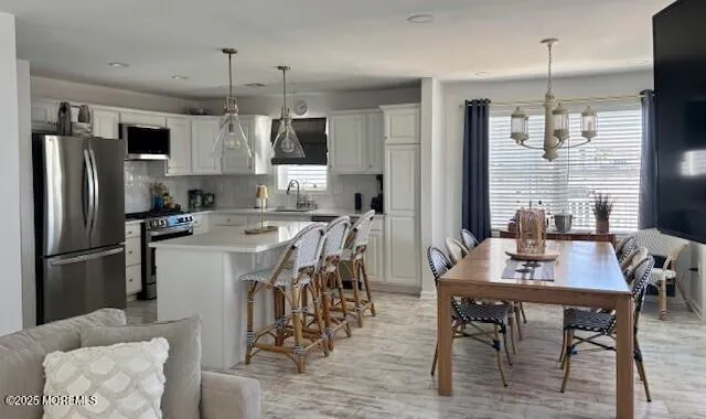 a kitchen with stainless steel appliances kitchen island granite countertop a dining table chairs and a refrigerator