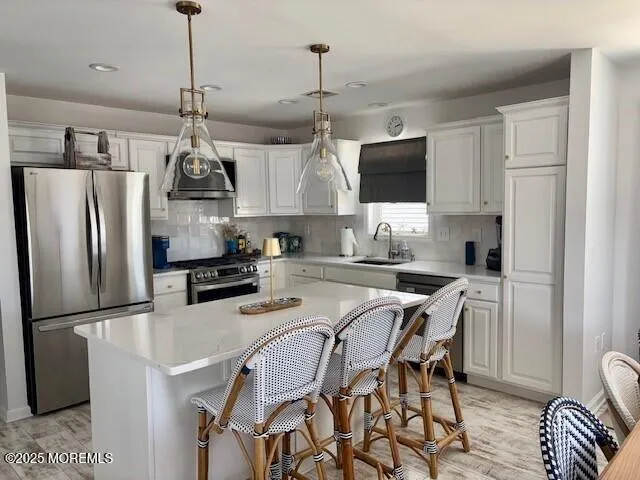 a kitchen with stainless steel appliances granite countertop a sink a stove a refrigerator and chairs