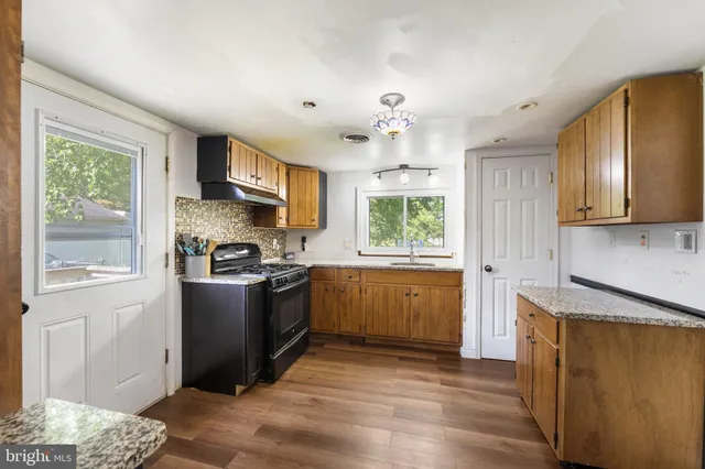 a kitchen with stainless steel appliances granite countertop a refrigerator a sink dishwasher a stove with wooden cabinets and floor