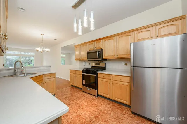 a kitchen with granite countertop a refrigerator a sink dishwasher a stove top oven a refrigerator with wooden cabinets and floor