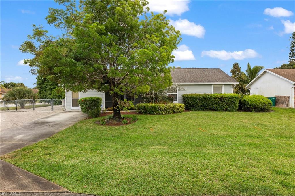 View of front facade featuring concrete driveway, fence, and a front lawn