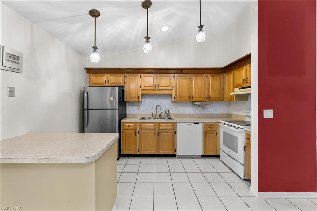 1700 42nd Terrace Southwest Naples, FL 34116 - Photo 9 of 27 Kitchen featuring a sink, white appliances, pendant lighting, and light countertops