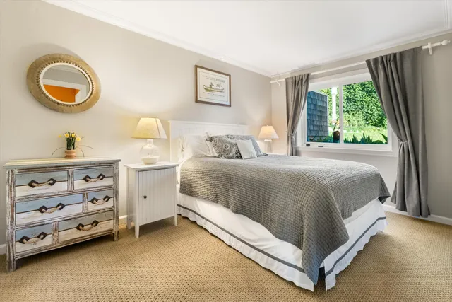 a bedroom with a bed and a dresser next to a window