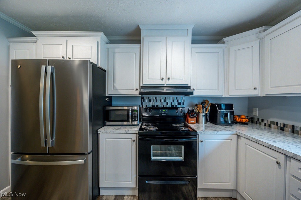 560 Wine Road Elizabeth, WV 26143 - Photo 18 of 50 Kitchen featuring appliances with stainless steel finishes, white cabinets, light countertops, under cabinet range hood, and crown molding