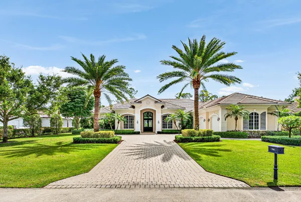 a front view of a house with a garden and trees