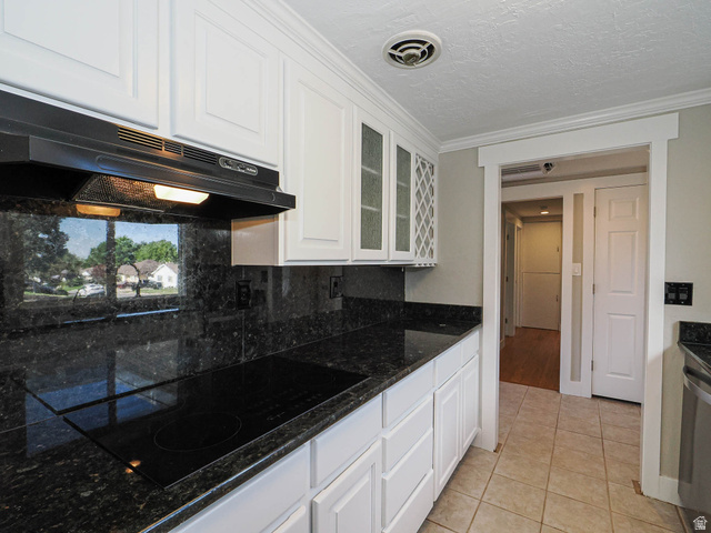 154 East 3000th Street South Bountiful, UT 84010 - Photo 3 of 37 Kitchen featuring white paneled cabinetry with some glass-front doors, black cooktop, dark speckled countertops, and a matching backsplash