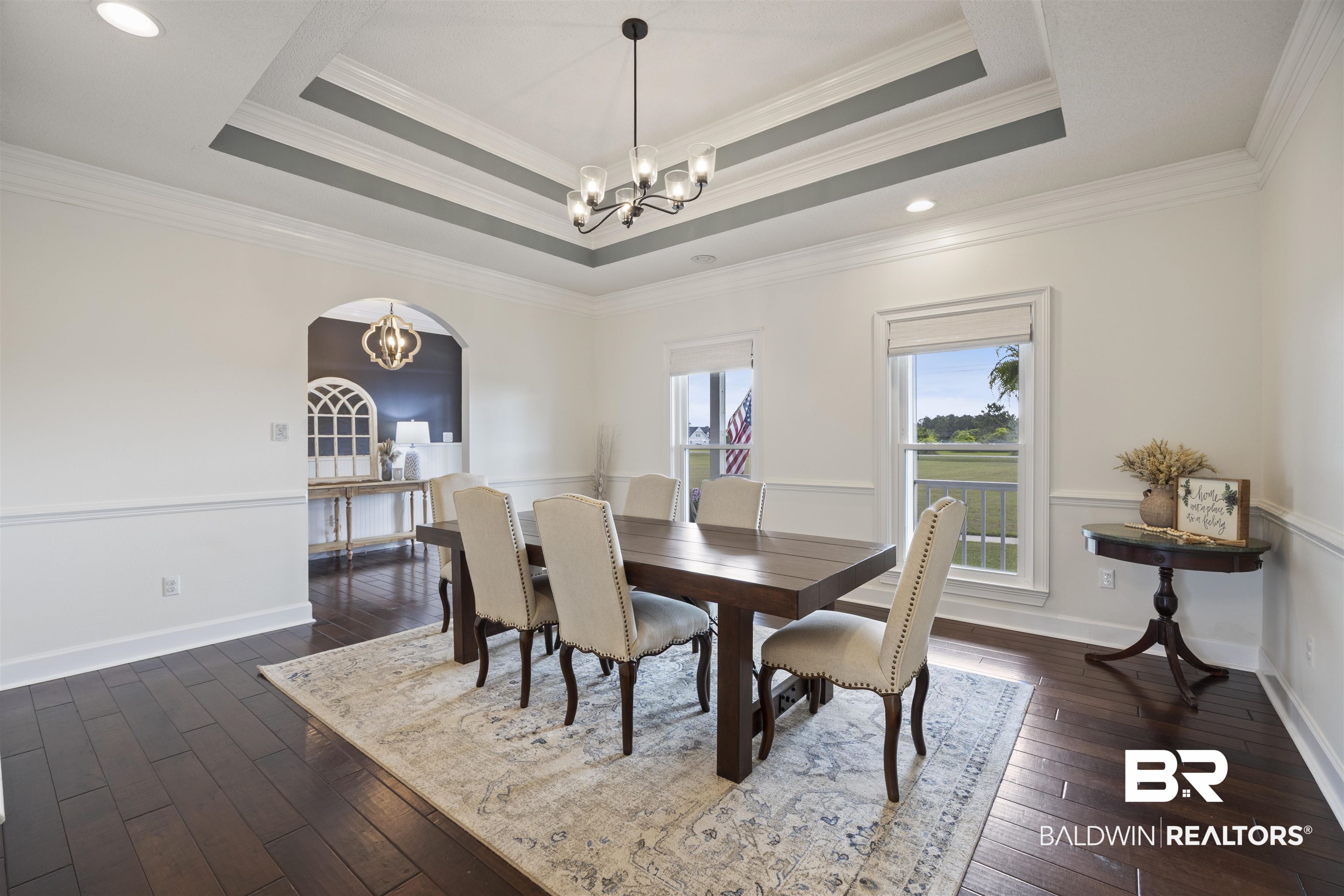 9855 Stucki Road Elberta, AL 36530 - Photo 12 of 54 Dining space featuring a chandelier, dark wood-style floors, crown molding, and arched walkways