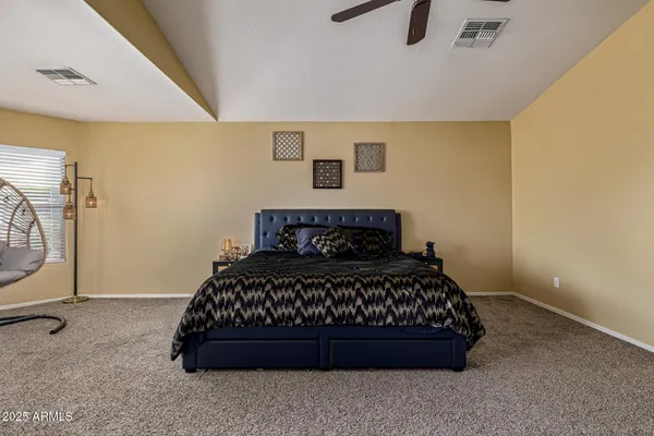 a bed sitting in a bedroom next to a lamp with wooden floor