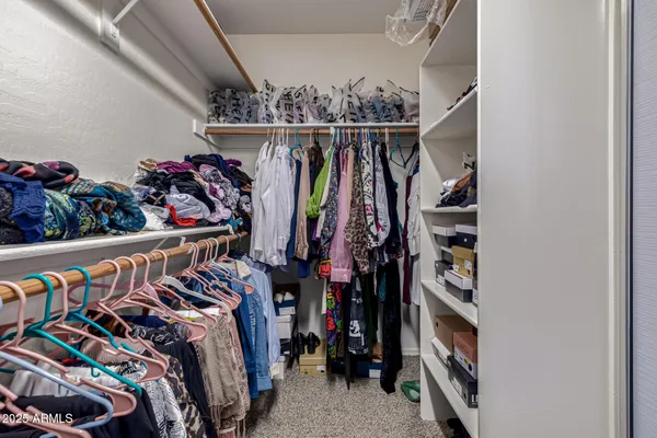 a view of walk in closet with clothes and shoes