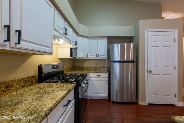 a kitchen with a refrigerator and a stove top oven