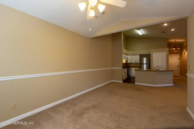 an empty room with chandelier fan and windows