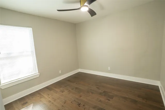 an empty room with a window and ceiling fan