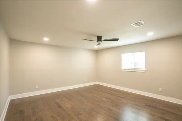 an empty room with a window and ceiling fan