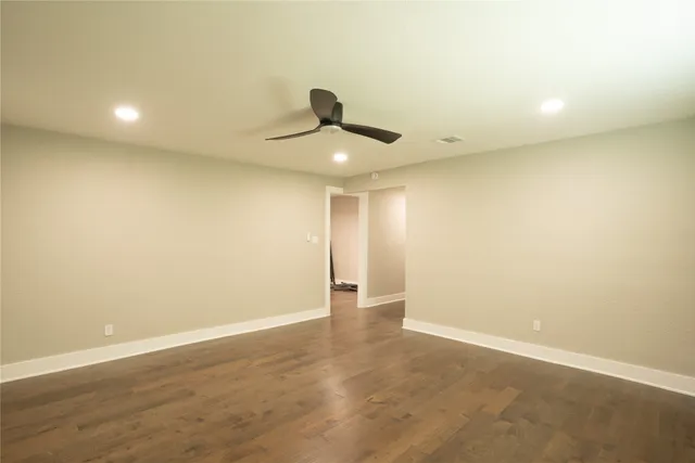 an empty room with wooden floor and ceiling fan