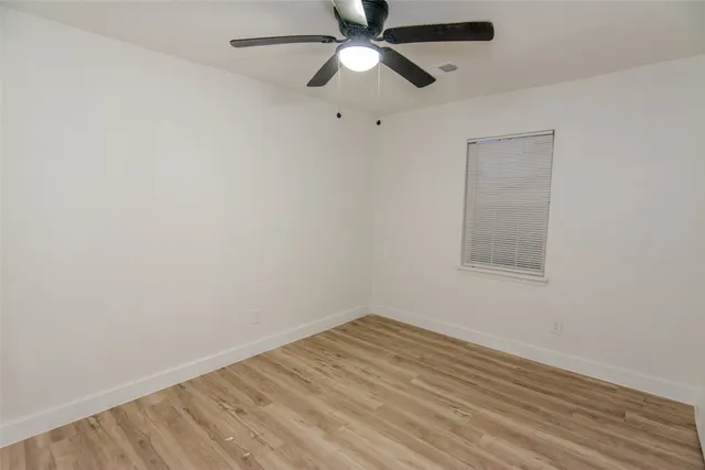an empty room with a window and a fan