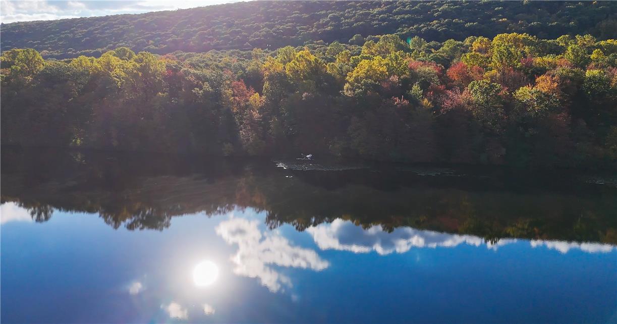 18 White Oak Road Nesquehoning, PA 18240 - Photo 49 of 52 Reflecting the sky, a serene lake rests at the base of a verdant, tree-lined hillside.