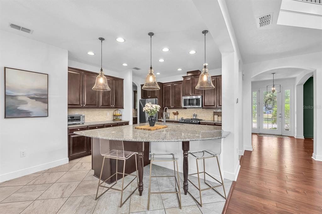 5310 Fishhawk Ridge Drive Lithia, FL 33547 - Photo 16 of 52 a kitchen with stainless steel appliances kitchen island granite countertop a stove a sink a dining table and chairs
