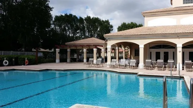 a front view of a house with swimming pool and porch with furniture