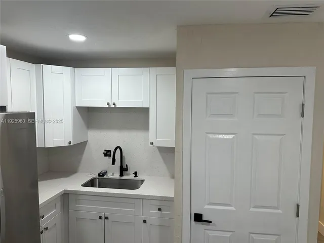 a kitchen with white cabinets and sink