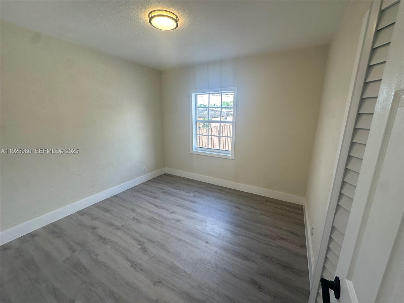 659 East 19th Street, Unit 659 Hialeah, FL 33013 - Photo 14 of 26 an empty room with wooden floor and windows